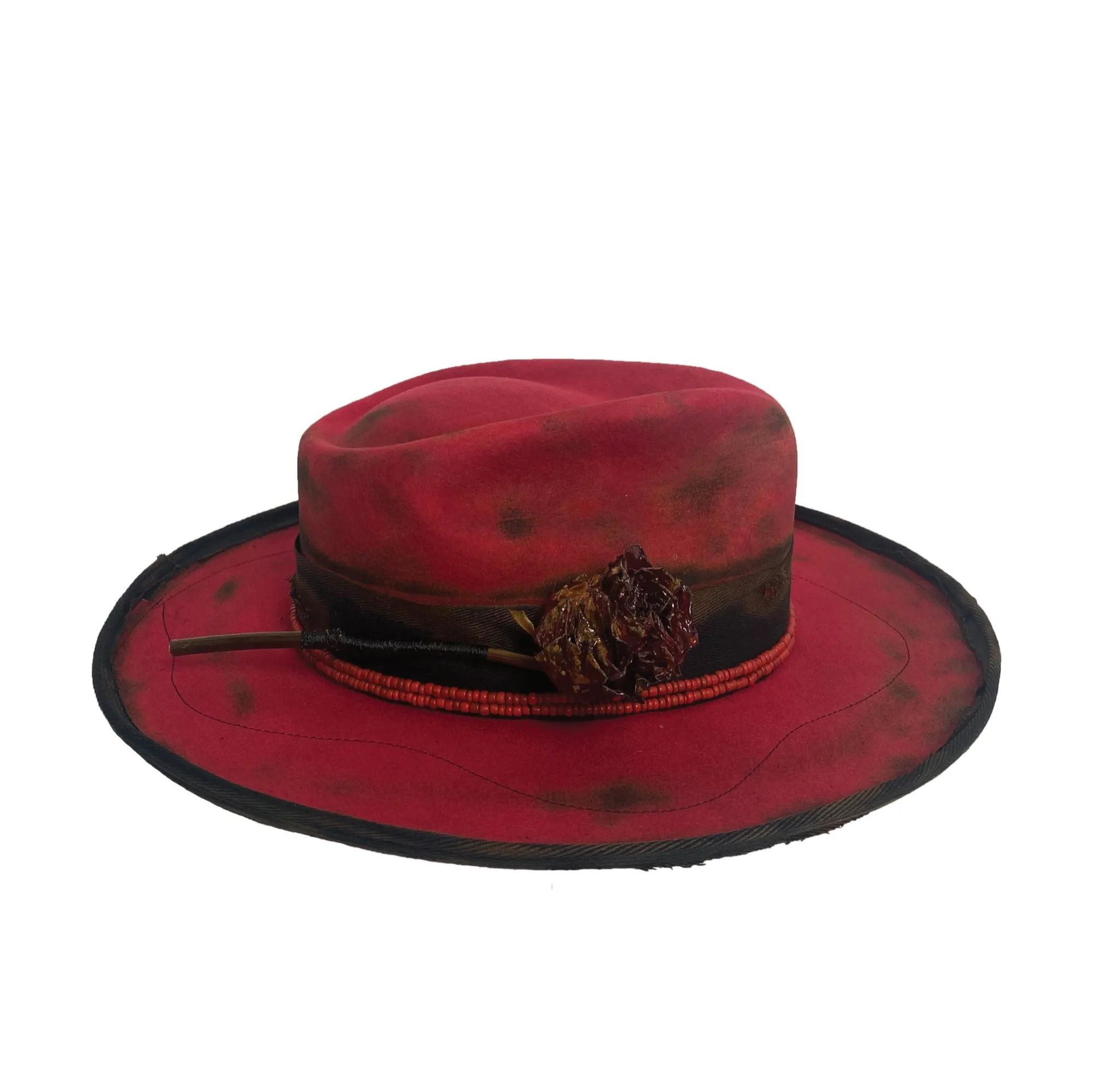 Deep red wide-brim fedora with a distressed, darkened edge and a dried flower tucked into the band