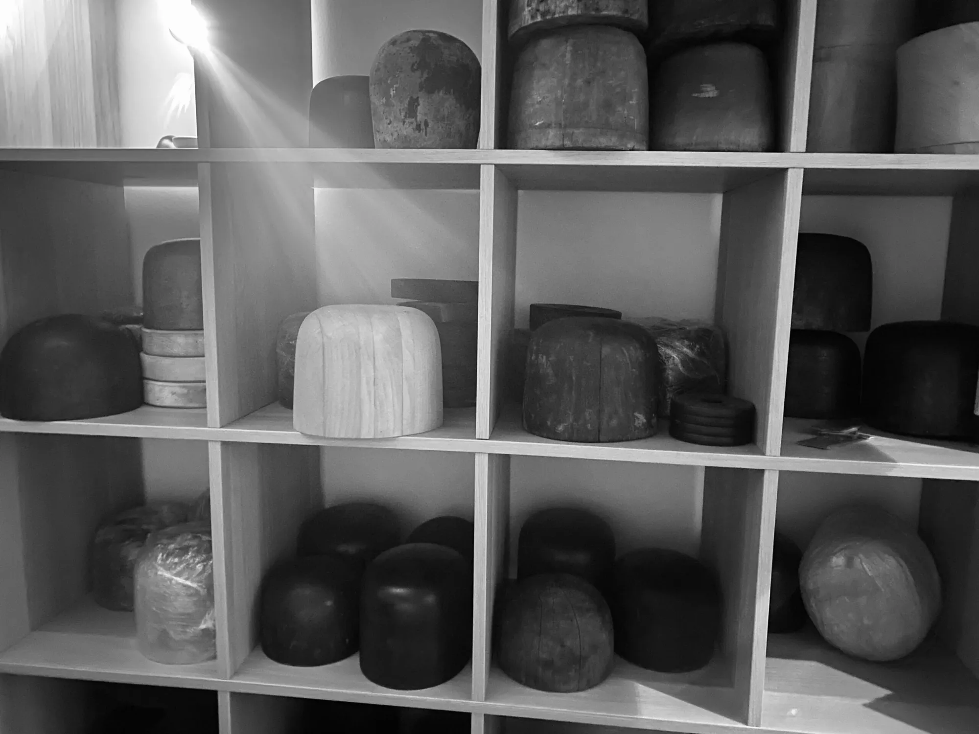 Wooden hat blocks lined up on shelves
