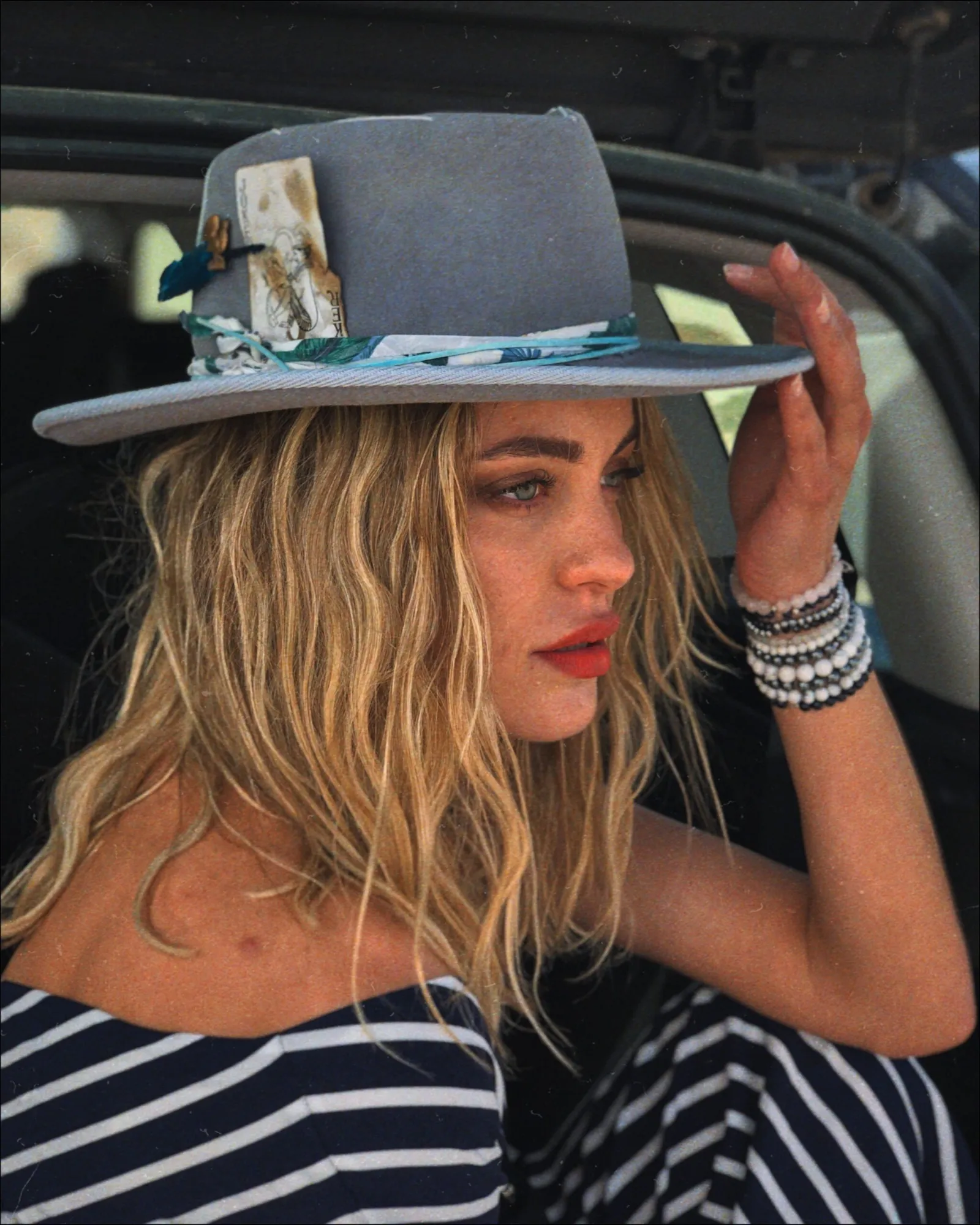 Woman adjusting a decorated blue hat in a car