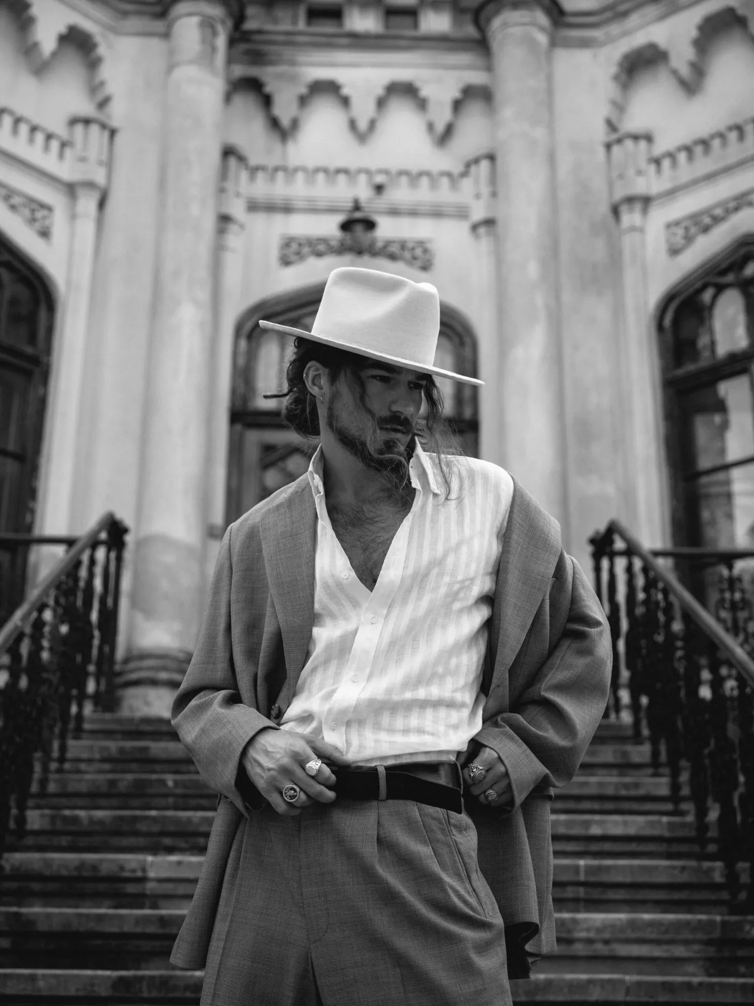 Man in a pale hat on church steps, black and white