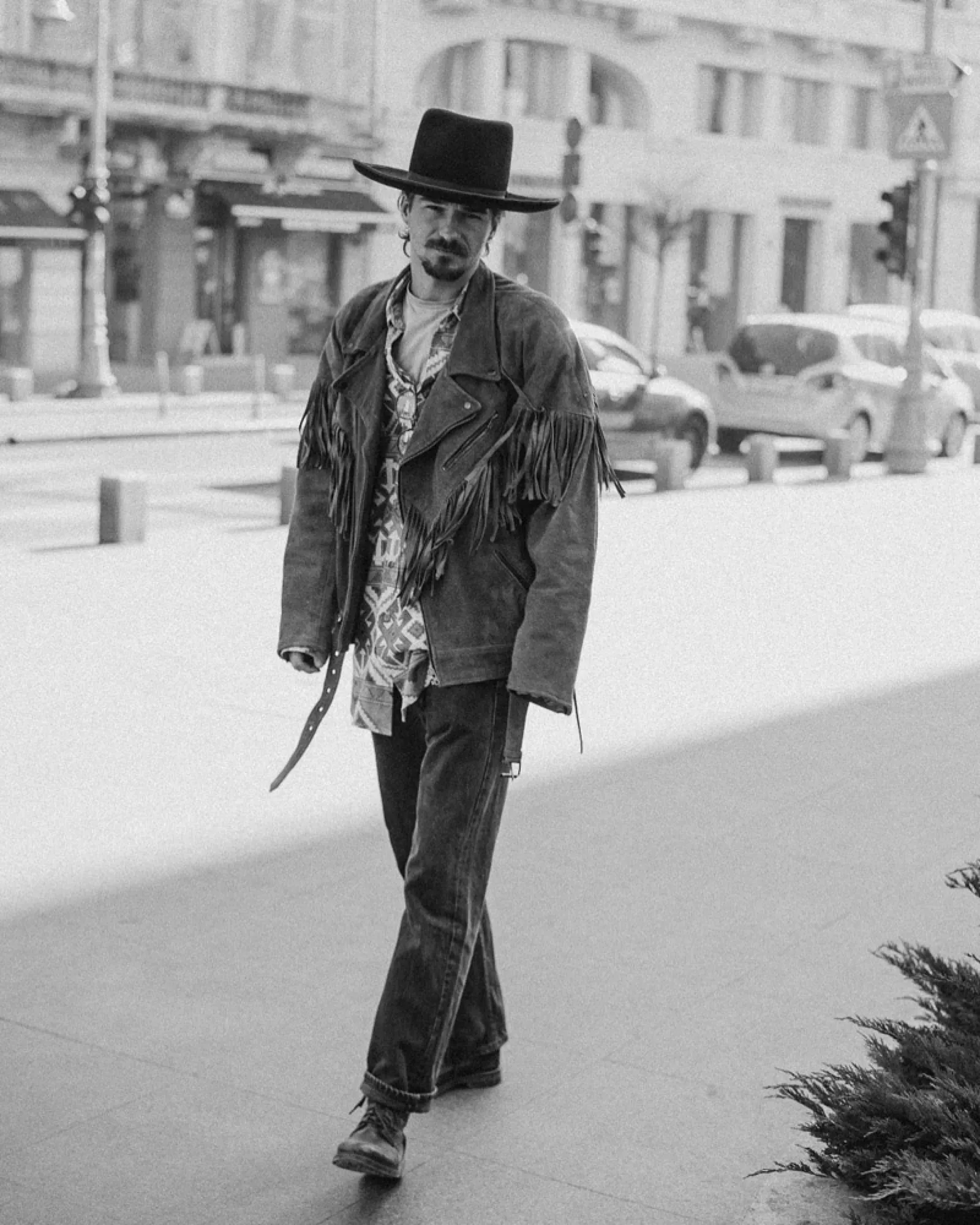 Man walking down a city street in a black hat
