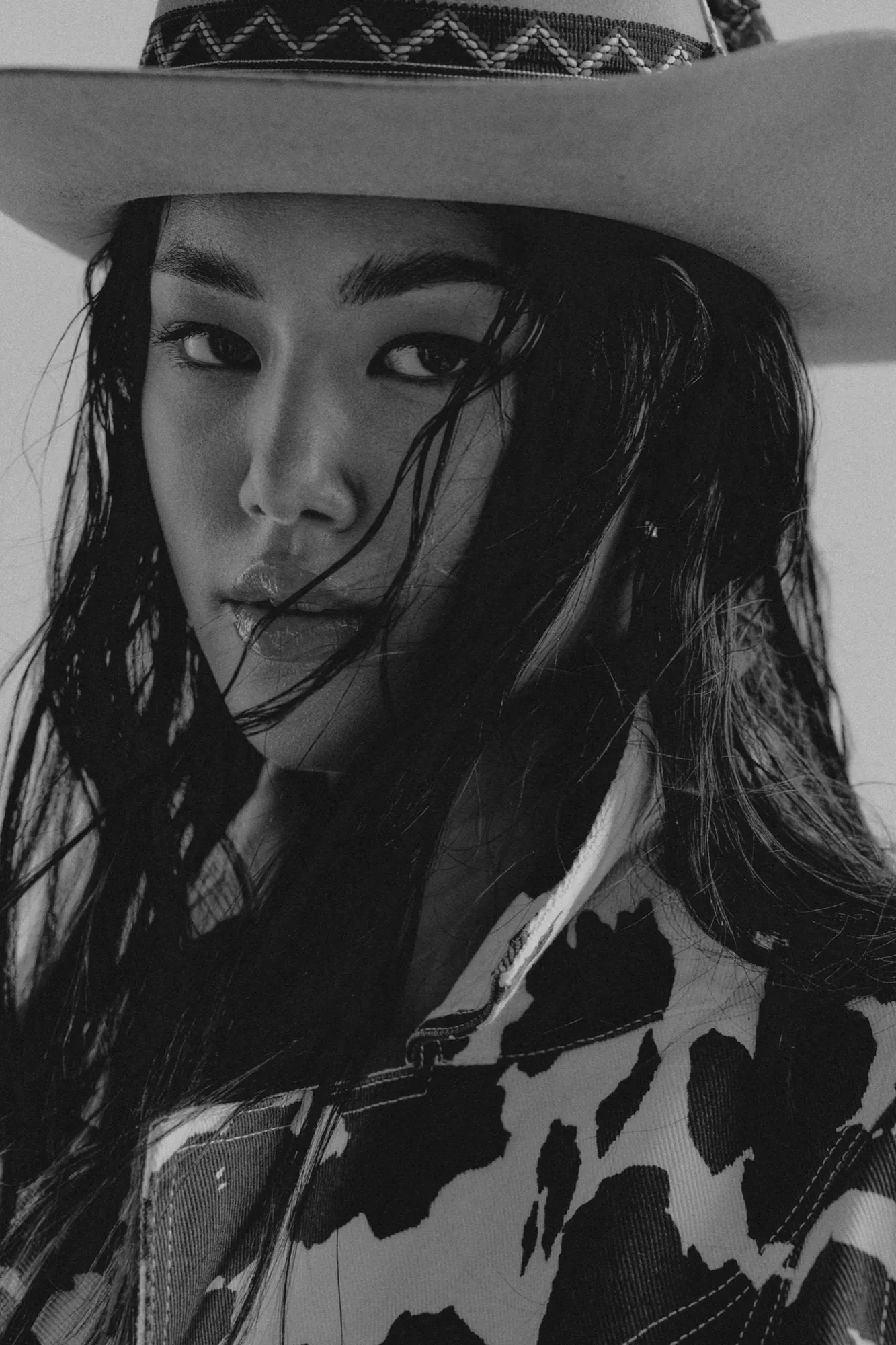 Close-up of a woman in a patterned hat, black and white