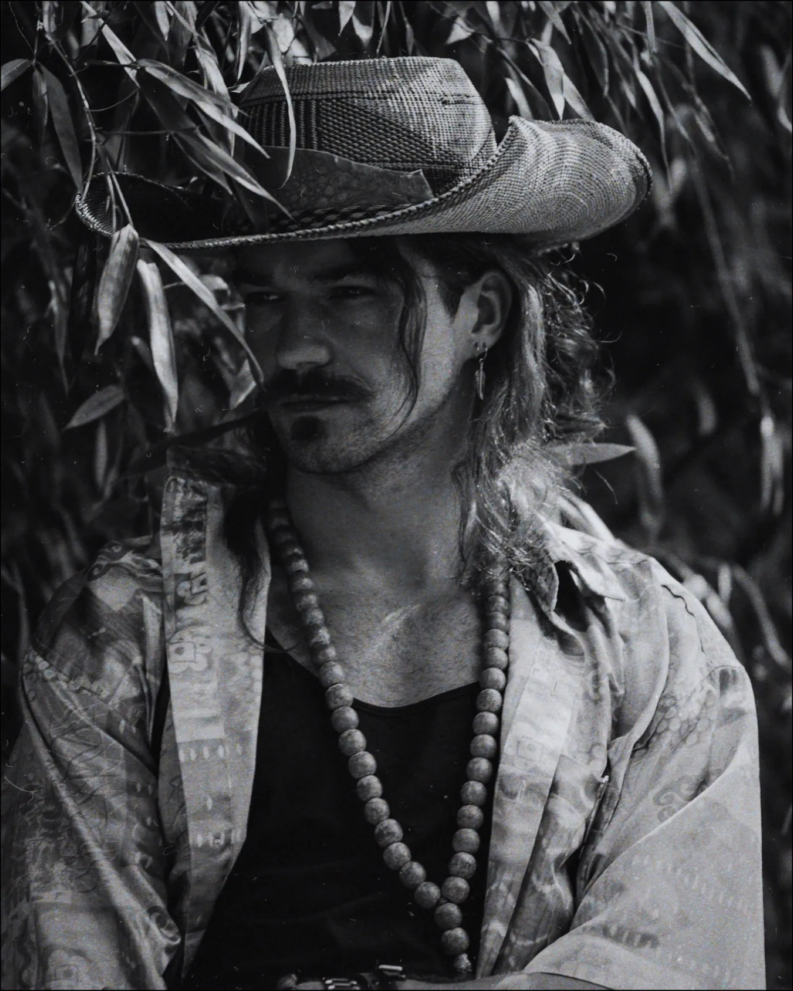Man in a hat among leaves, black and white