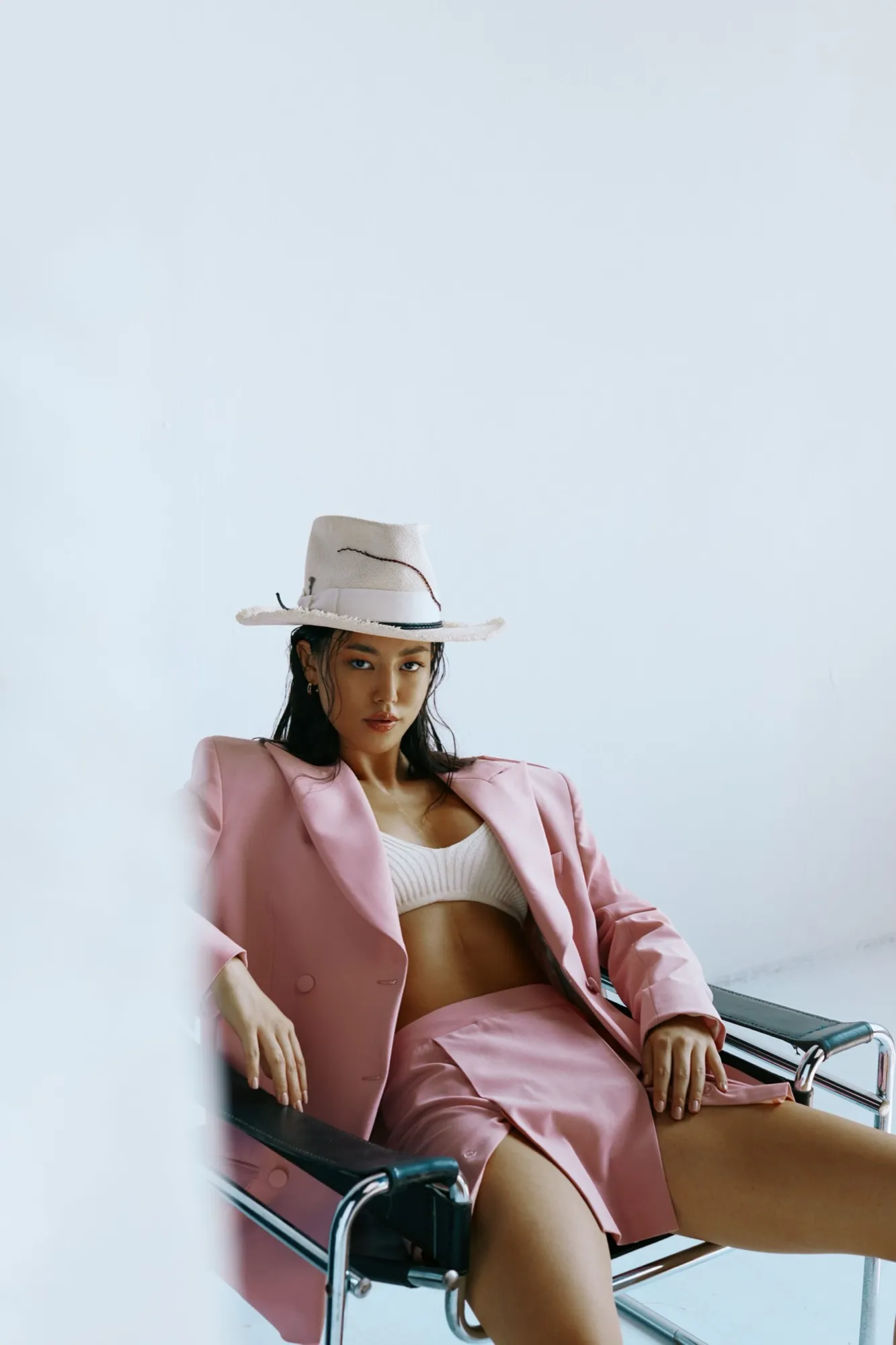 Woman in a pink suit and pale hat, seated