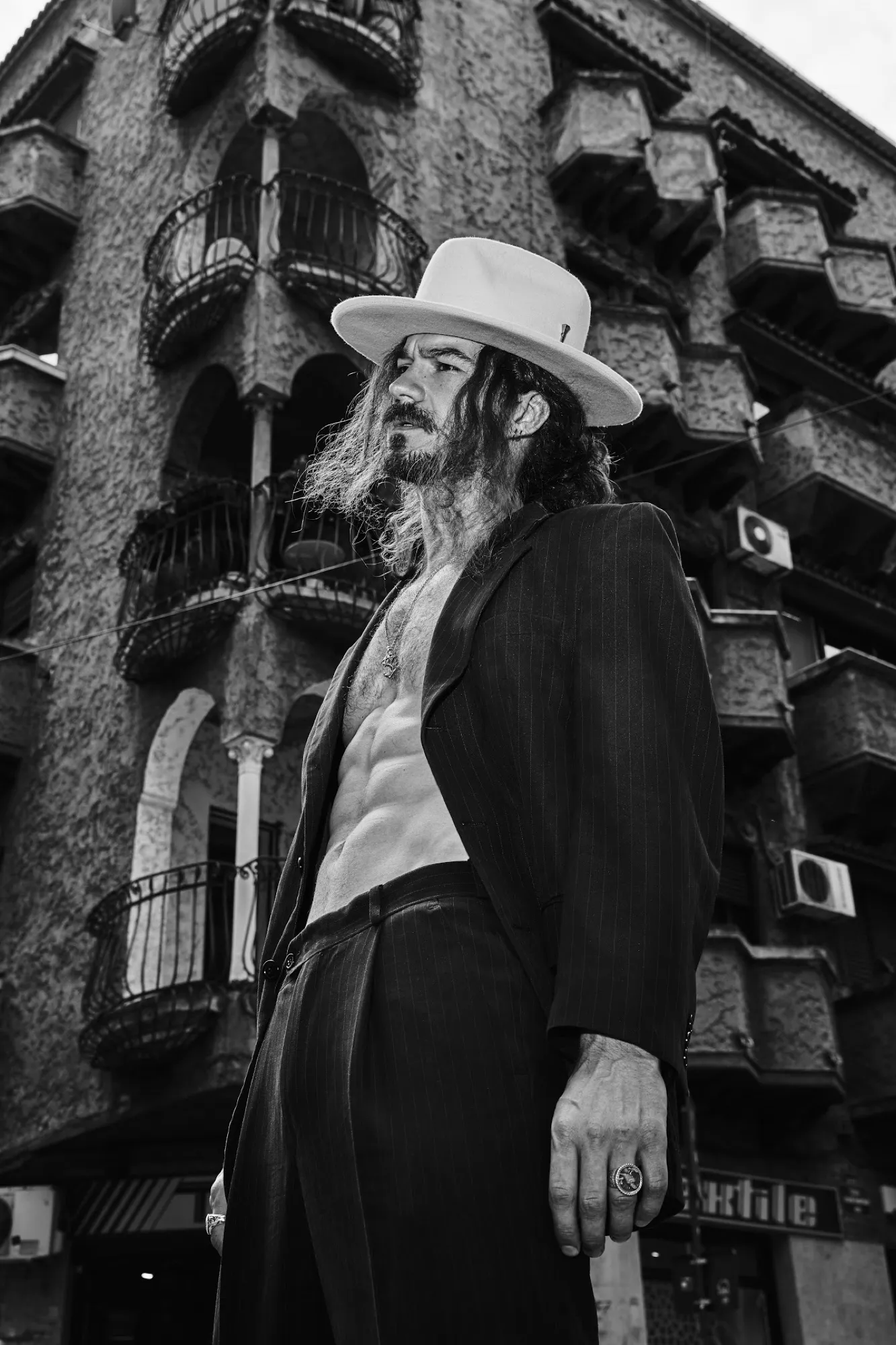 Man in a white hat beside an old building, black and white