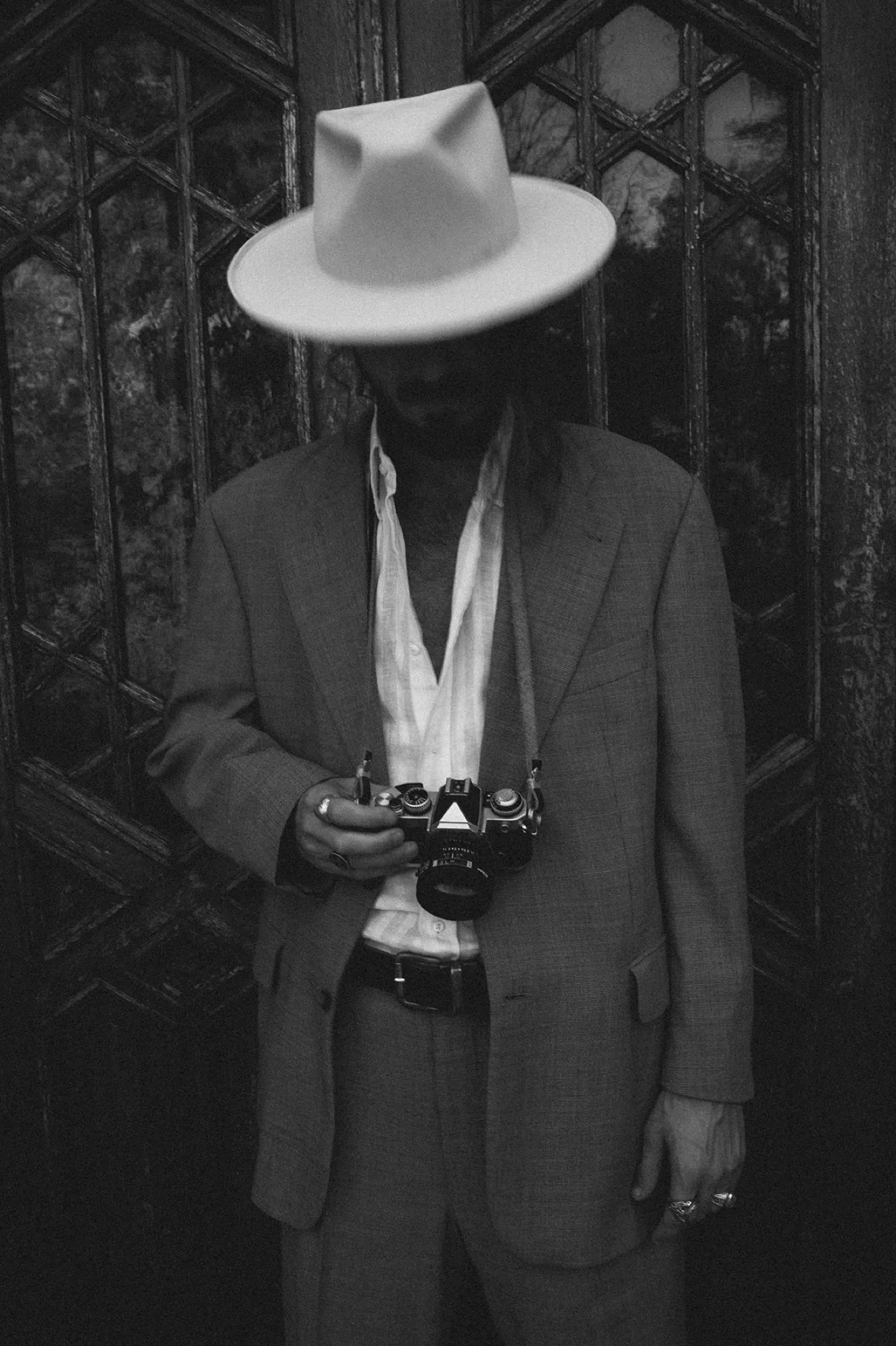 Man in a pale hat holding a camera, black and white