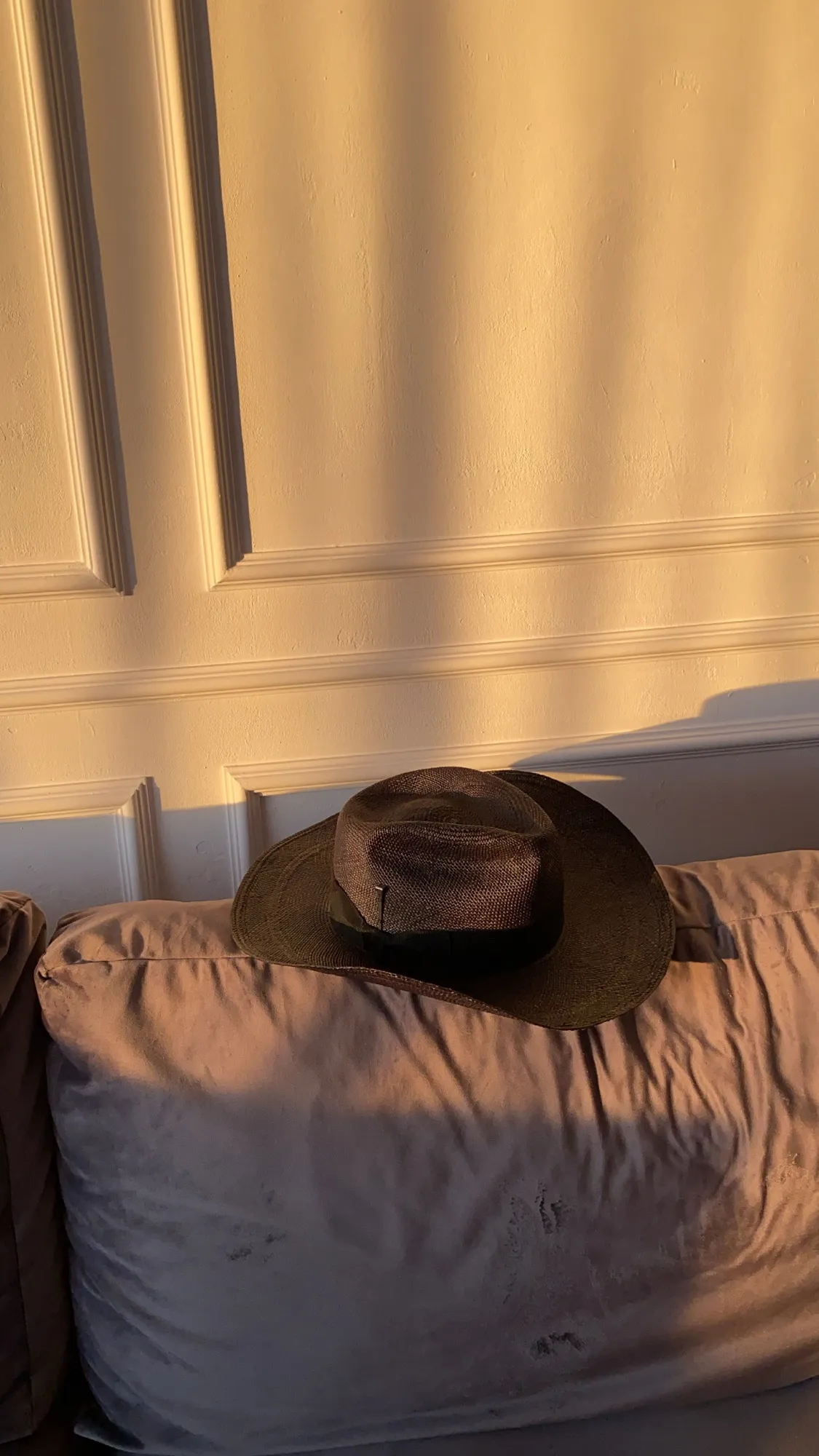 A hat resting on a bed in warm window light