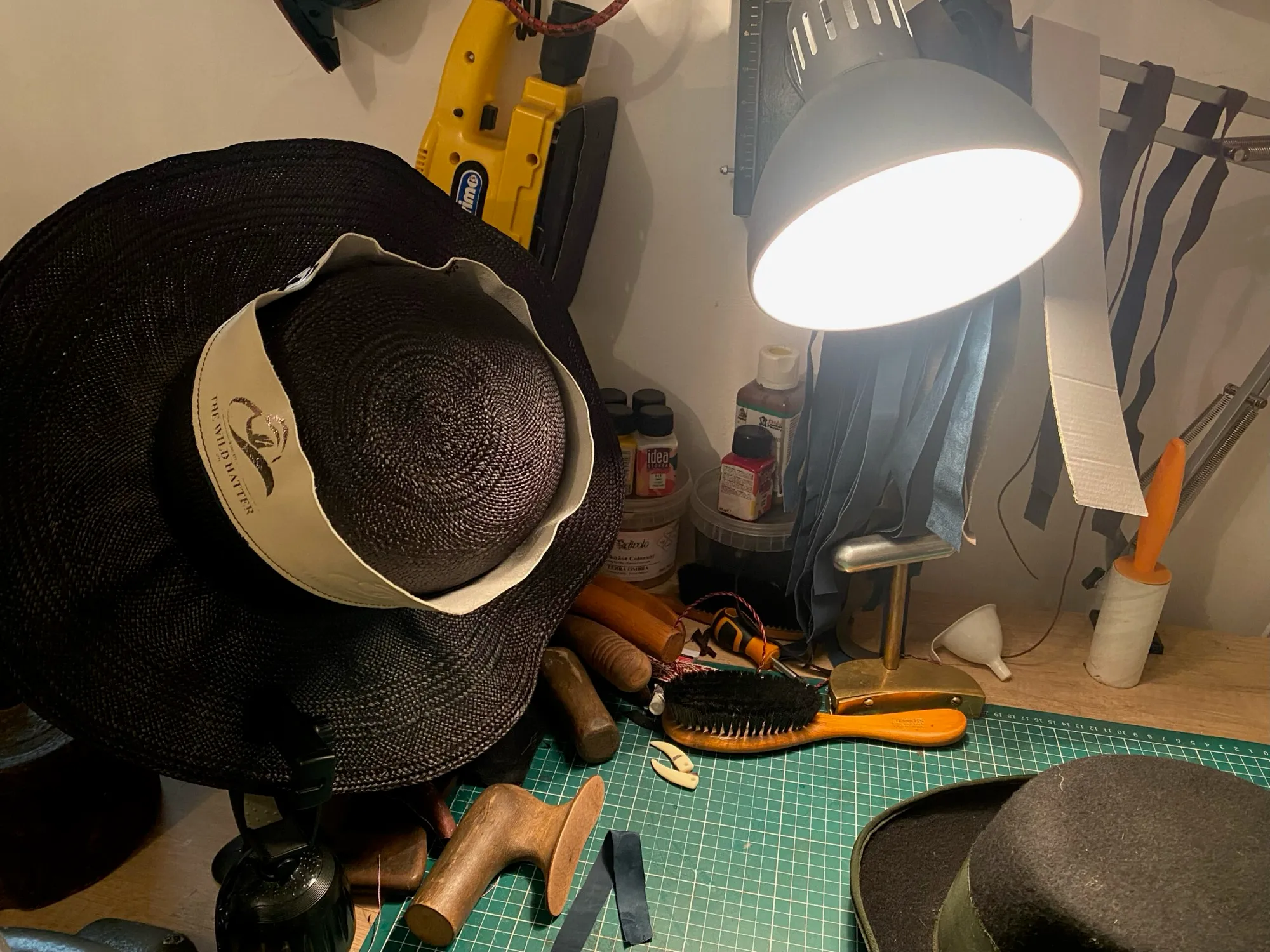 A hat in progress under the lamp on the workbench